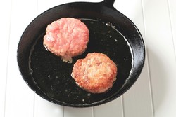 Burgers frying in a pan